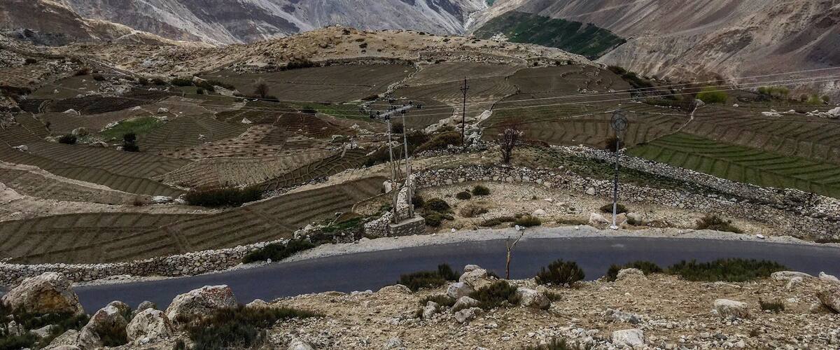 Terraced fields, a winding road, and snow-capped mountains.