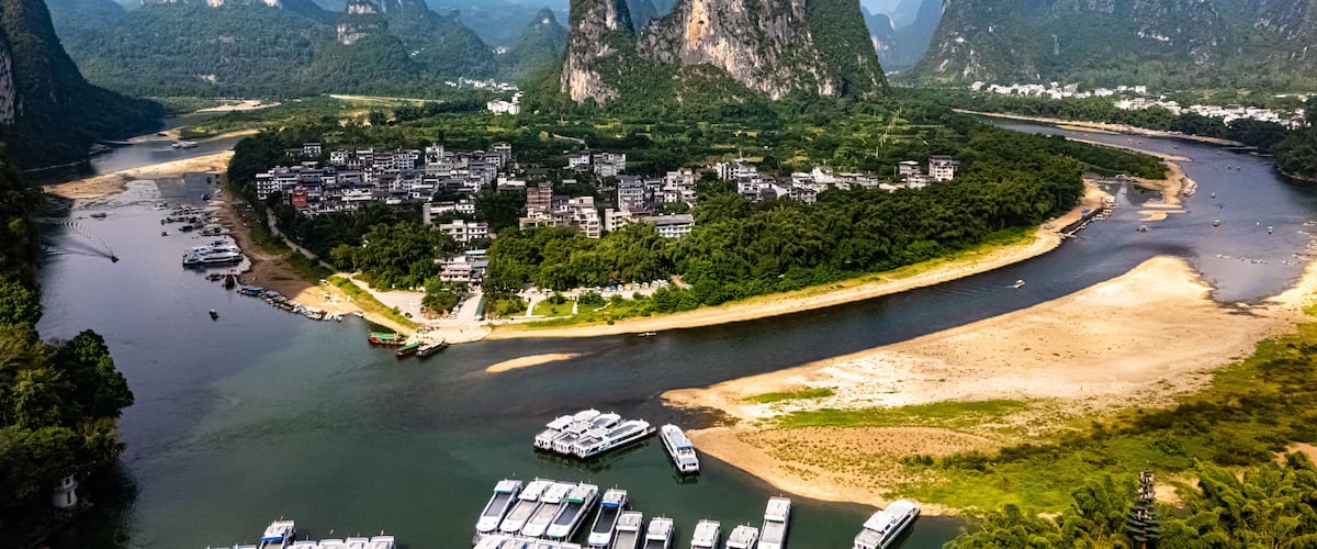 A river winding through a town surrounded by limestone karst mountains.