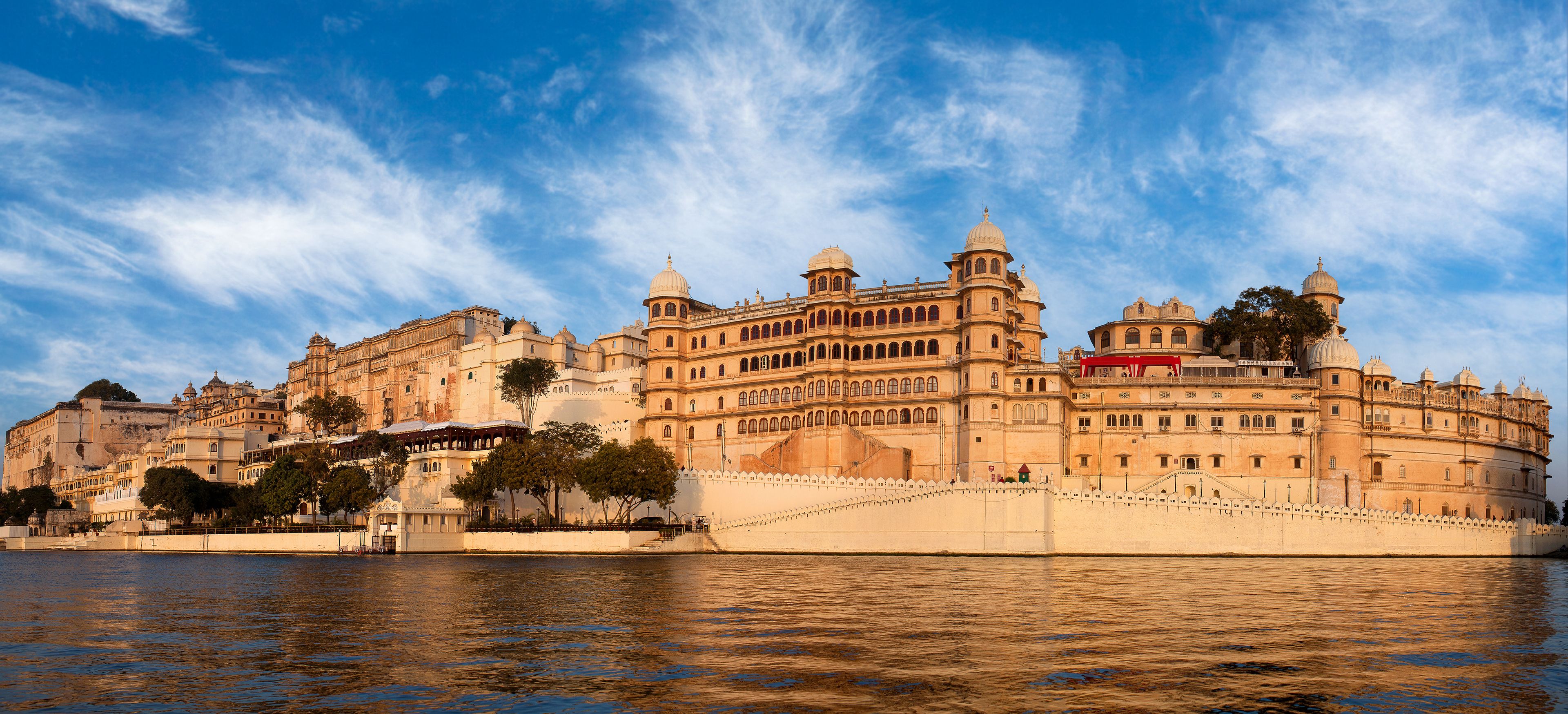 A historic building with multiple domes and arches, situated by a river.
