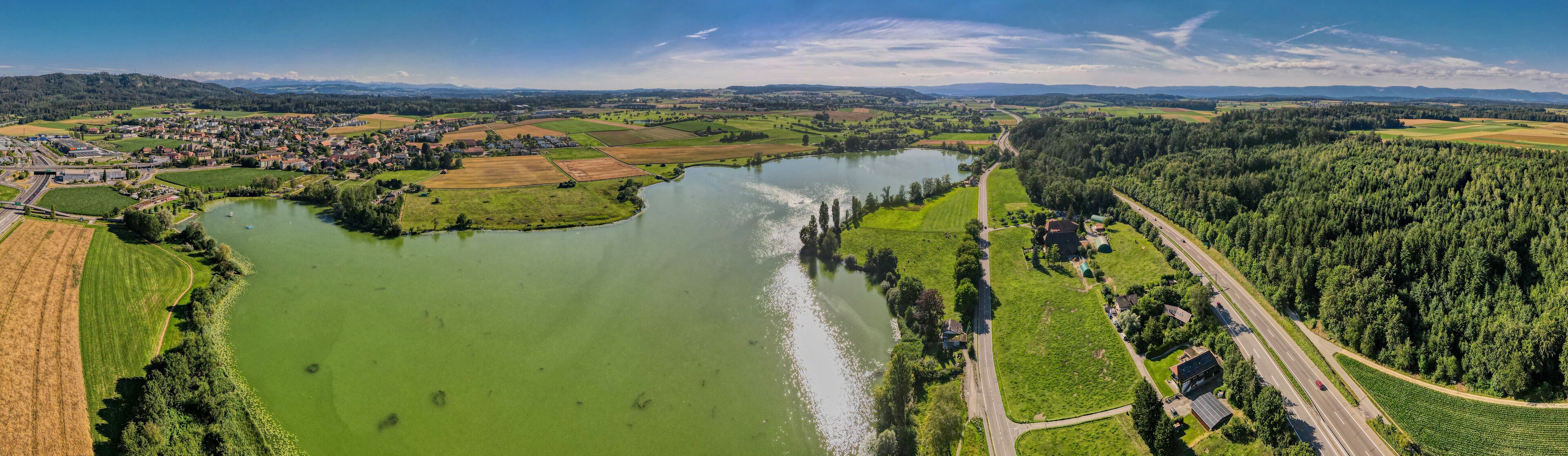 A river winding through a town with fields and forests.