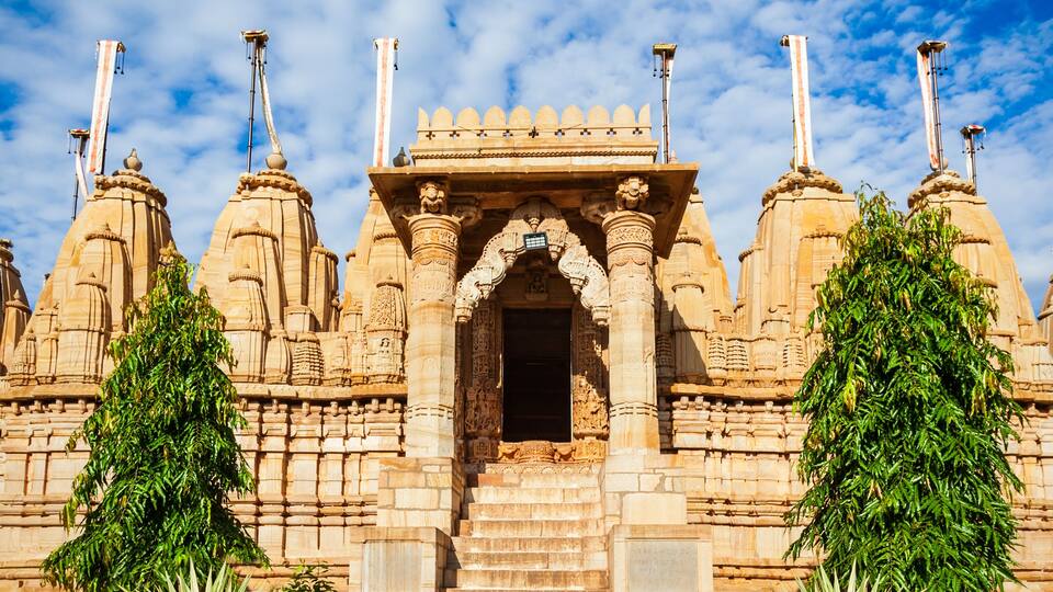 A temple with intricate carvings and a central doorway, surrounded by lush greenery.