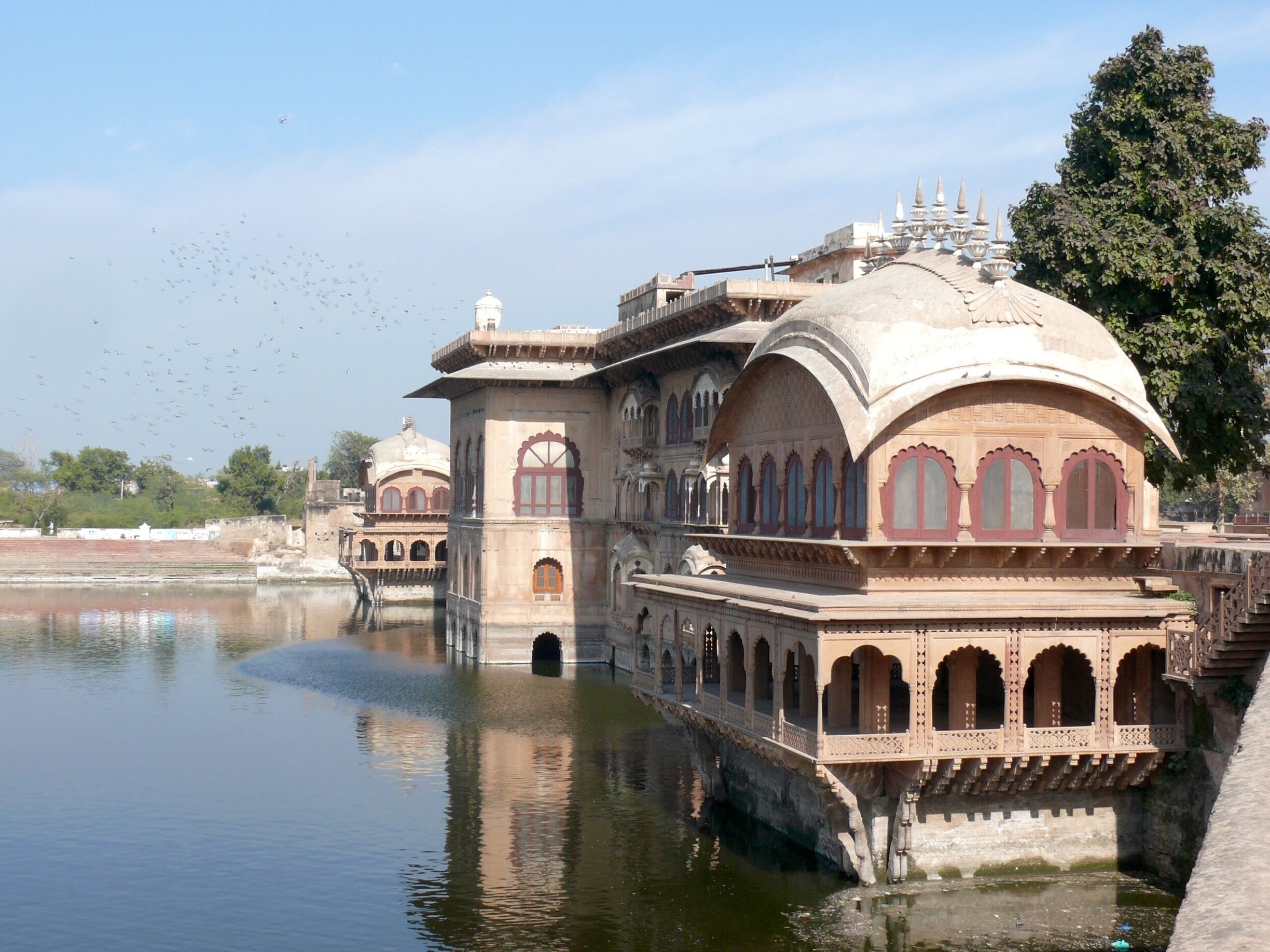 A historic building with arched windows and a dome, situated over a body of water.