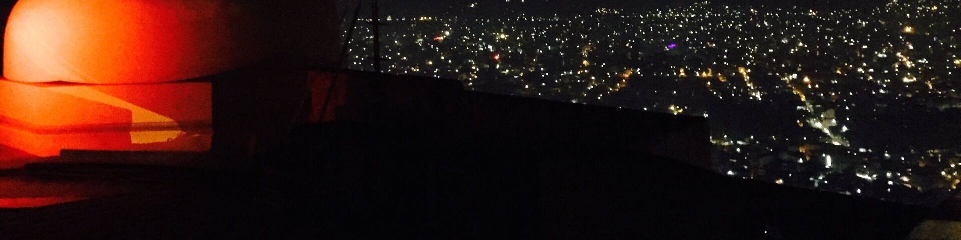 A night view of a city with a prominent illuminated dome structure.