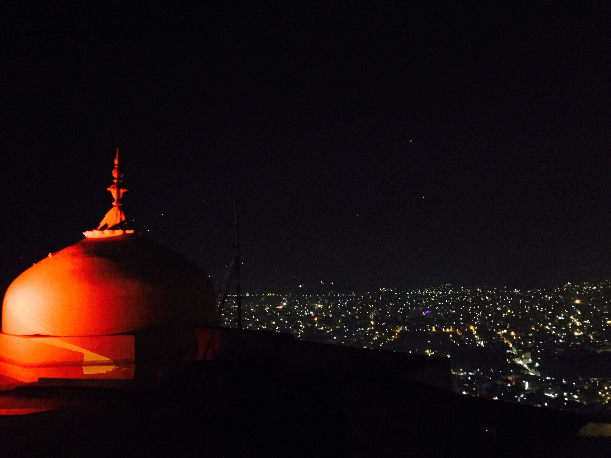 A night view of a city with a prominent illuminated dome structure.