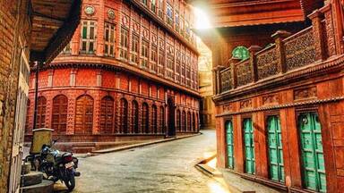 A narrow street flanked by red brick buildings with arched windows and intricate carvings.