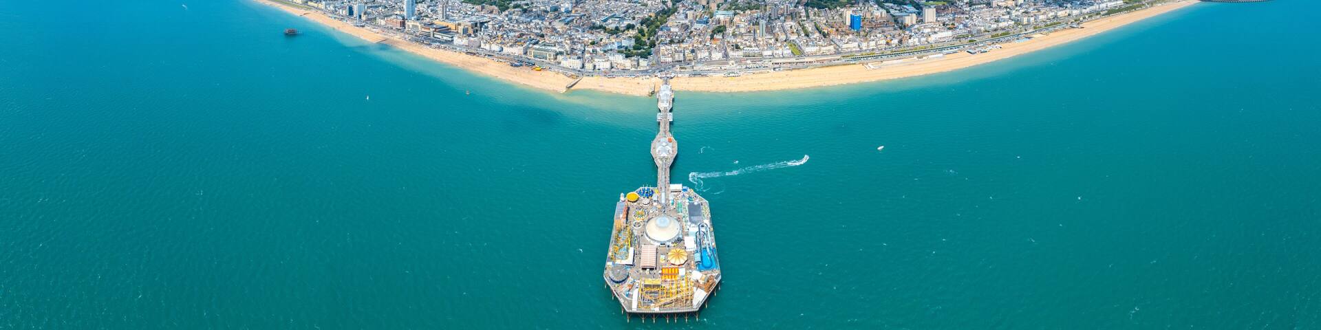 An aerial view of a coastal city with a prominent pier extending into the sea.