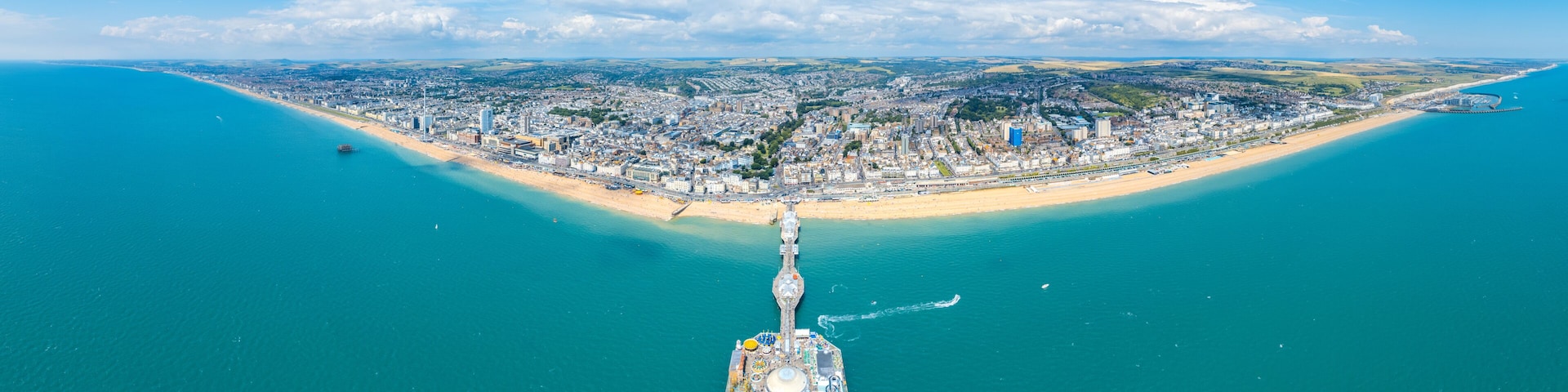 An aerial view of a coastal city with a prominent pier extending into the sea.