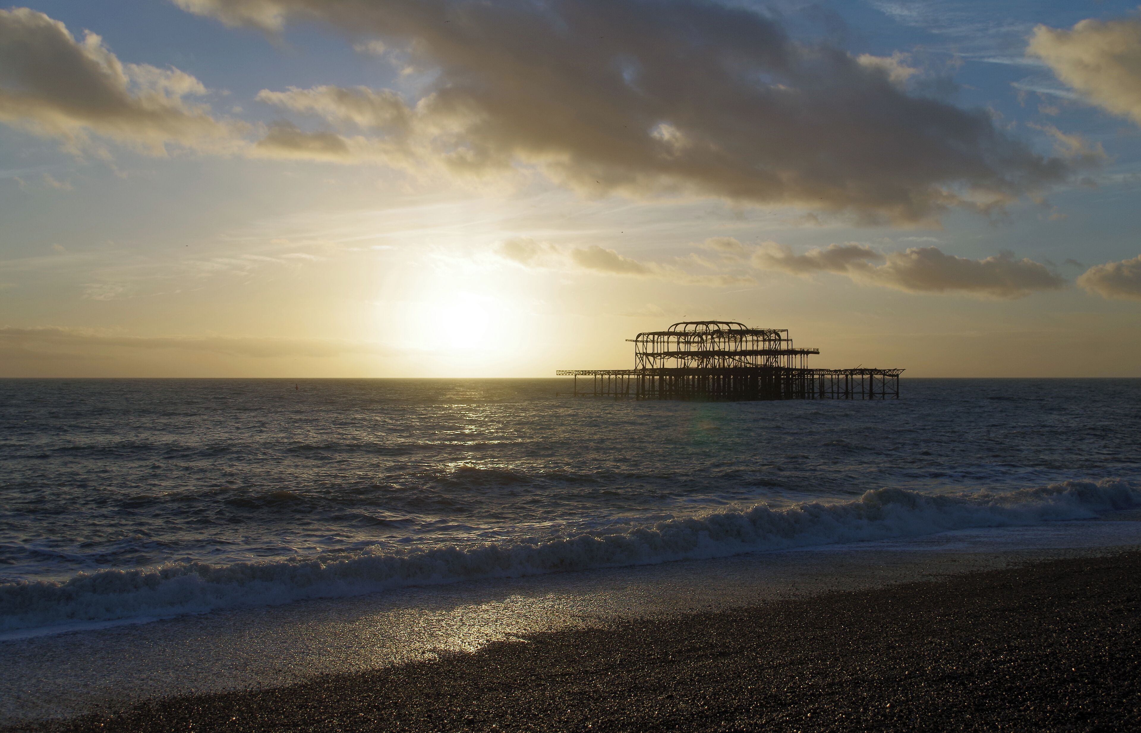 The remains of Brighton West Pier, seen from the beach as the sun sets.