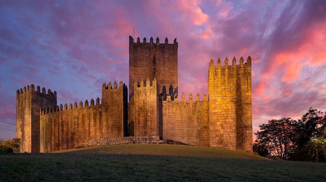 A medieval castle with multiple towers and a large central keep, set against a dramatic sunset sky.