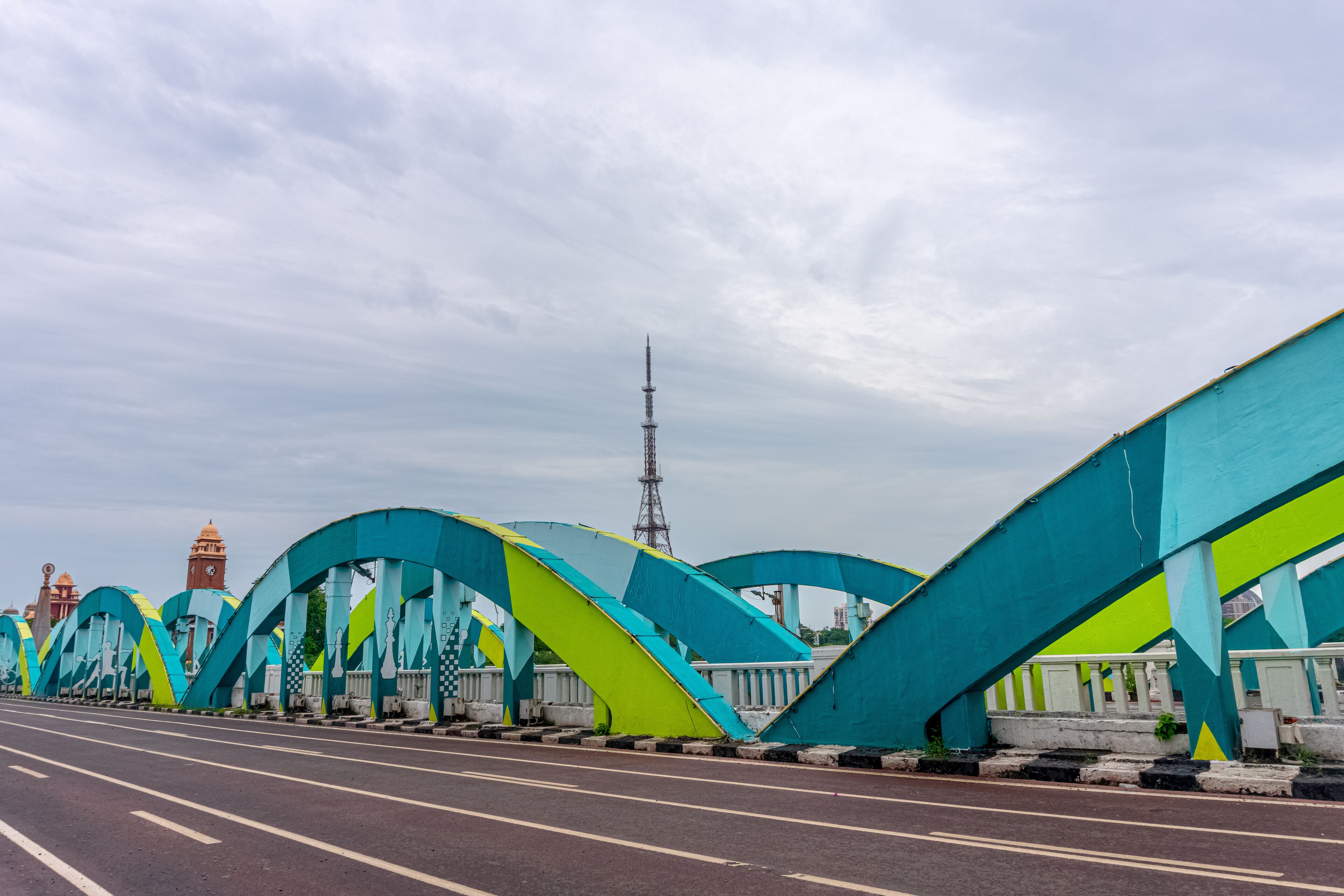 A bridge with colorful arches and a clock tower in the background.