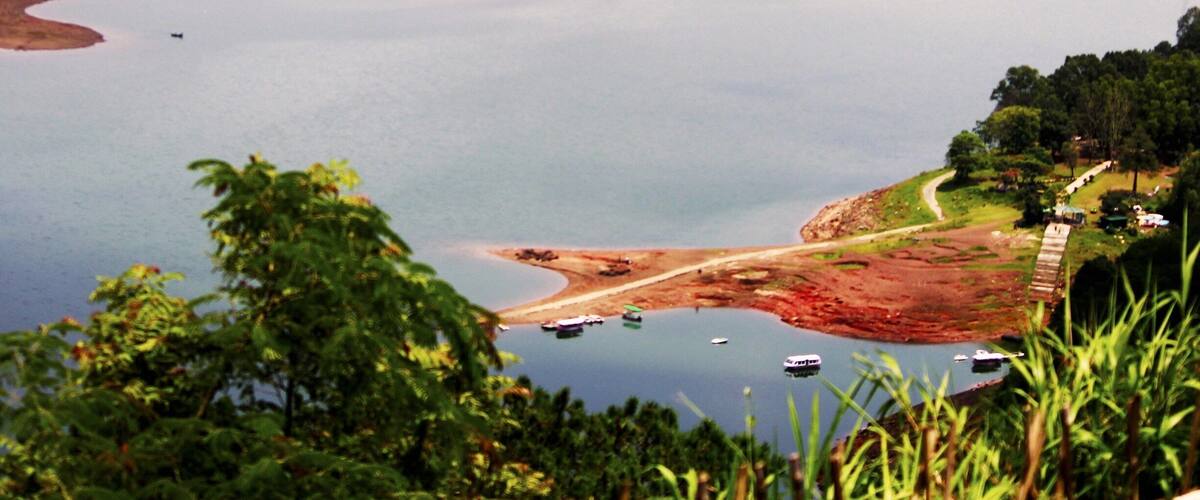 A lake surrounded by hills and trees. Boats are visible on the water.