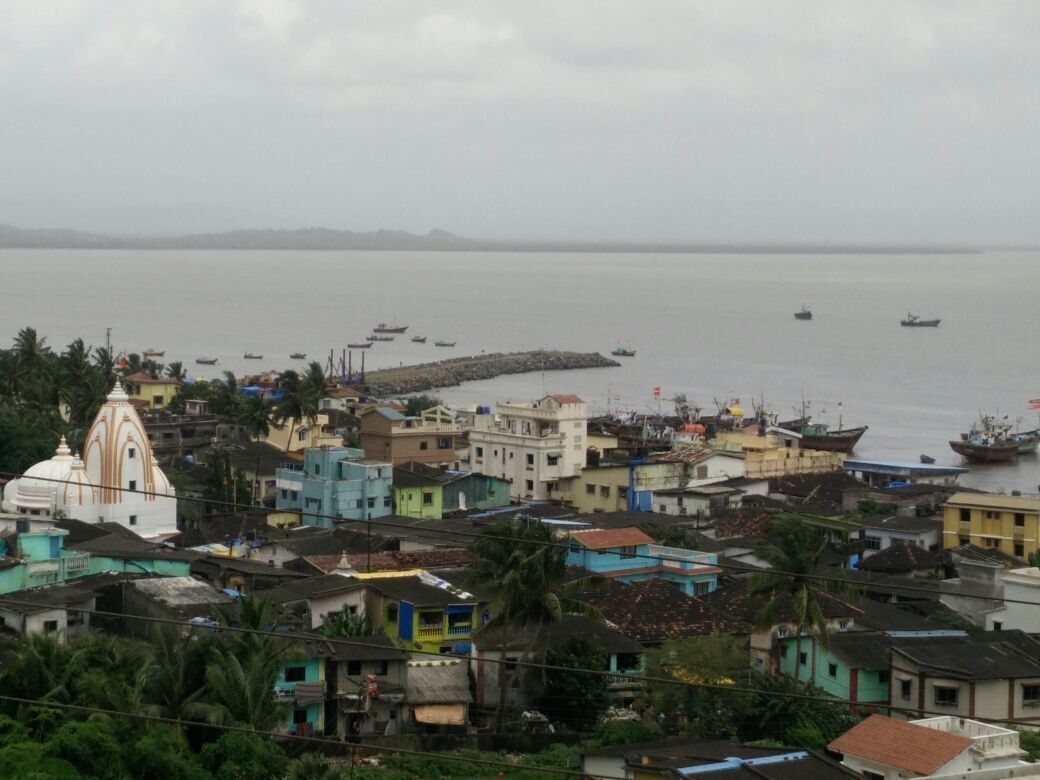 A coastal town with colorful buildings, a prominent church, and boats on the water.