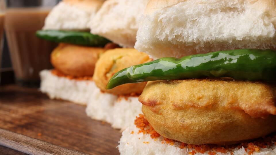 A close-up of a food item with bread and a green chili.