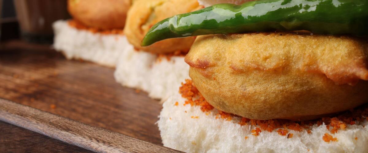 A close-up of a food item with bread and a green chili.