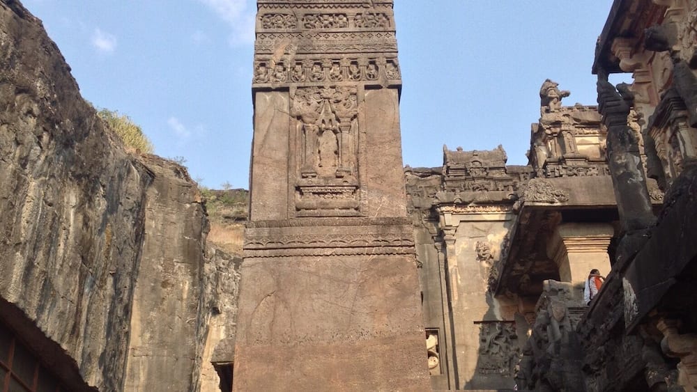 An ancient stone pillar with intricate carvings, set against a clear sky.