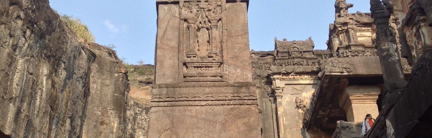 An ancient stone pillar with intricate carvings, set against a clear sky.