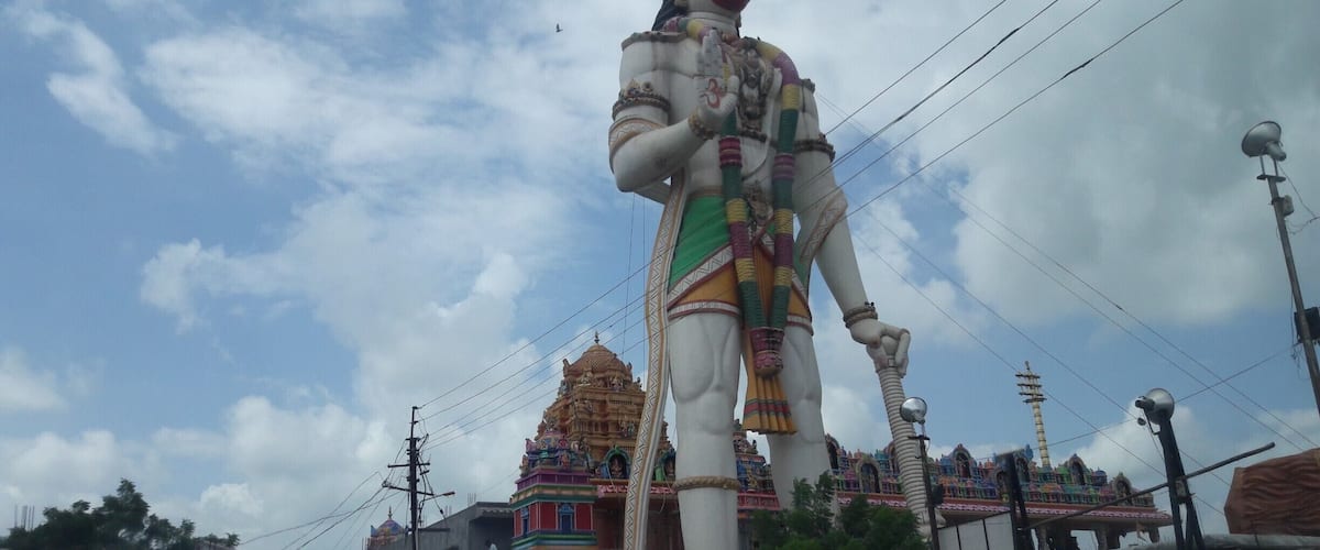 A large statue of a deity with a temple in the background.