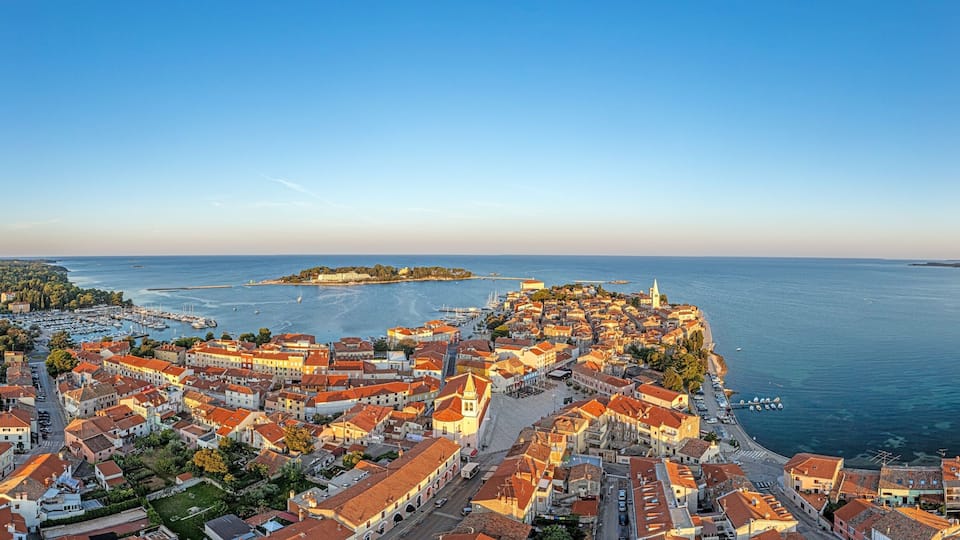 Drone panorama of Croatian coastal town Porec with harbor and promenade during sunrise