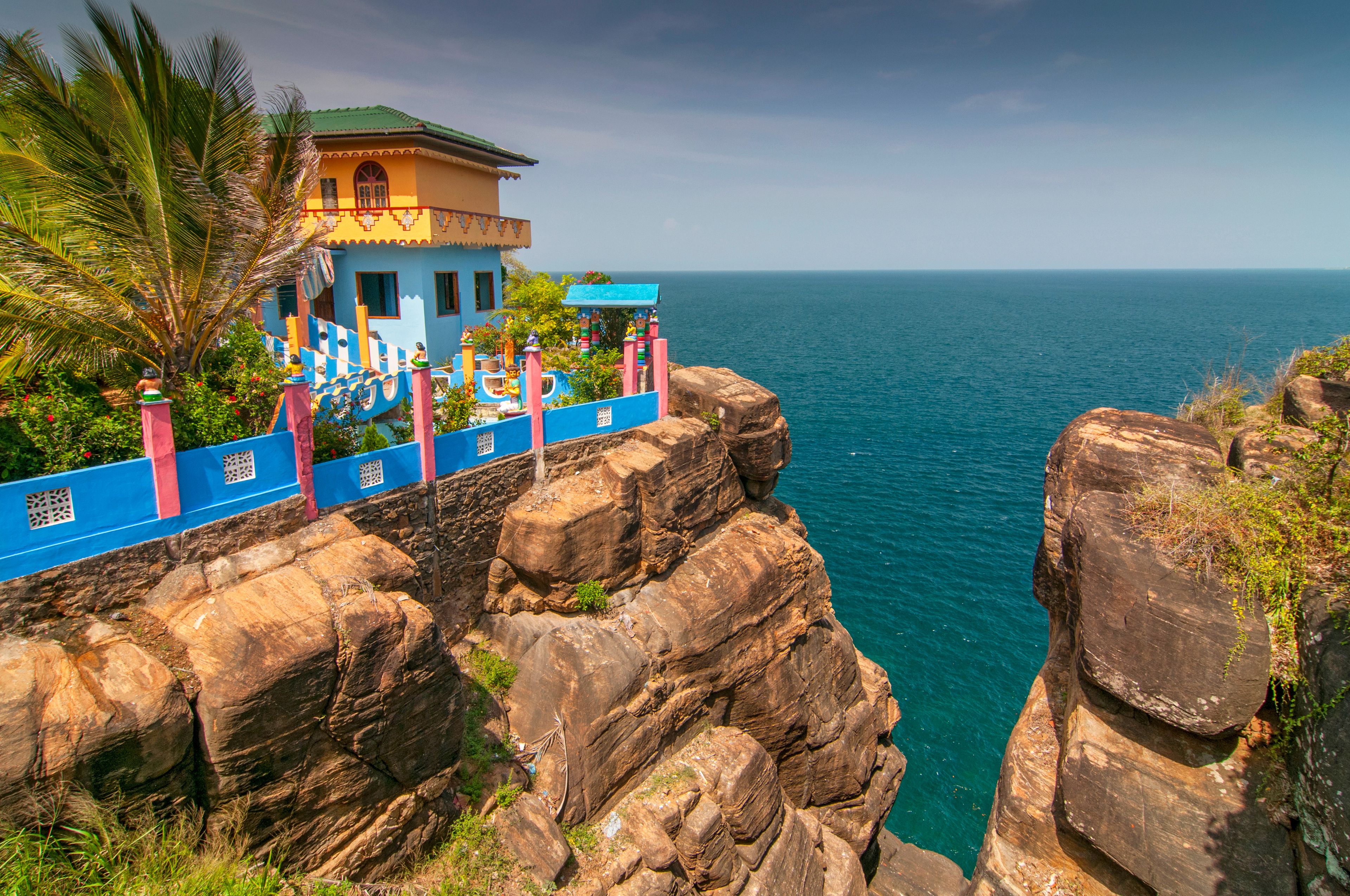 A coastal cliff with a colorful building and a view of the ocean.