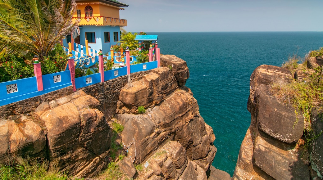 A coastal cliff with a colorful building and a view of the ocean.