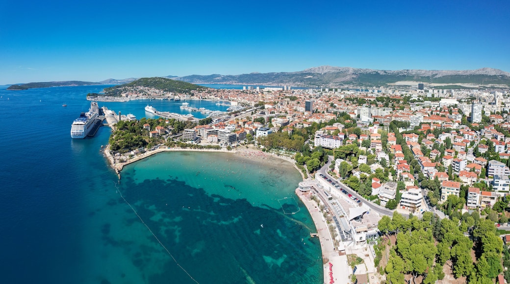 Aerial view of the vibrant, turquoise waters of Bacvice Beach meeting the bustling city, Split, Dalmatian Coast, Croatia.