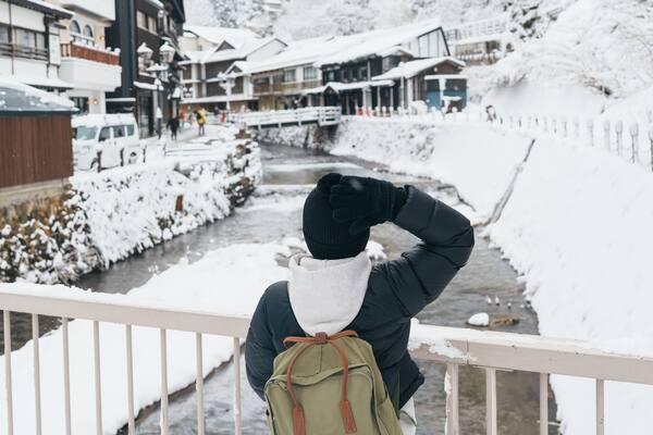 Woman tourist Visiting Ginzan Onsen in Yamagata, happy Traveler sightseeing Japanese Onsen village with Snow in winter season. landmark and popular for attraction in Japan. Travel and Vacation concept