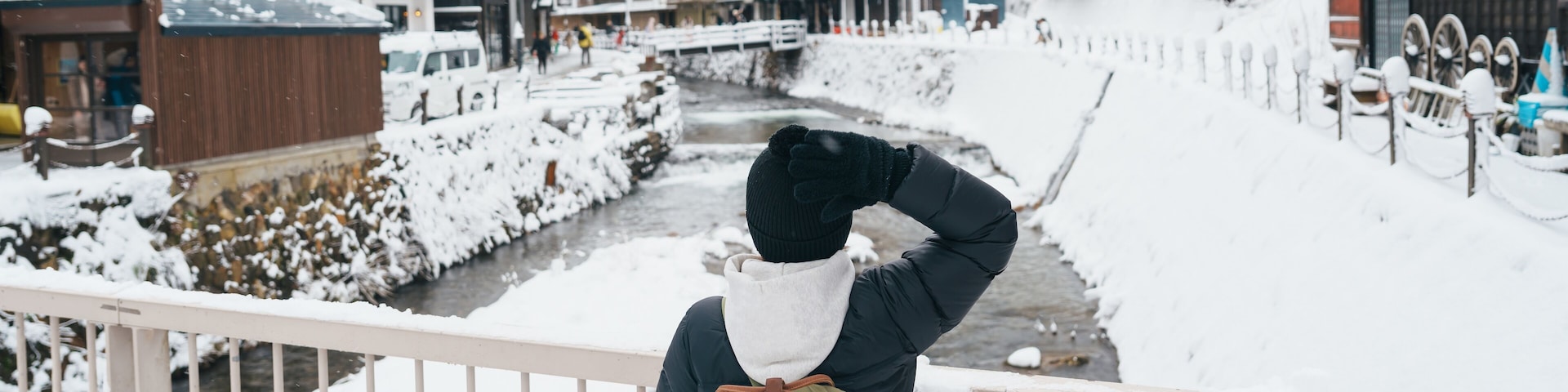 Woman tourist Visiting Ginzan Onsen in Yamagata, happy Traveler sightseeing Japanese Onsen village with Snow in winter season. landmark and popular for attraction in Japan. Travel and Vacation concept