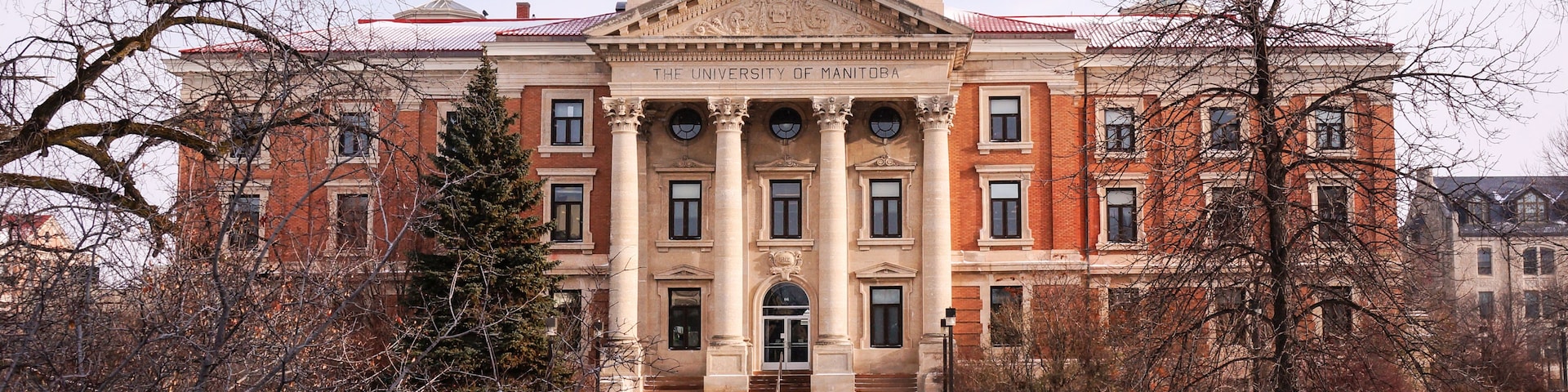 A large, historic building with a prominent clock tower and the name 'The University of Manitoba' displayed on its facade.