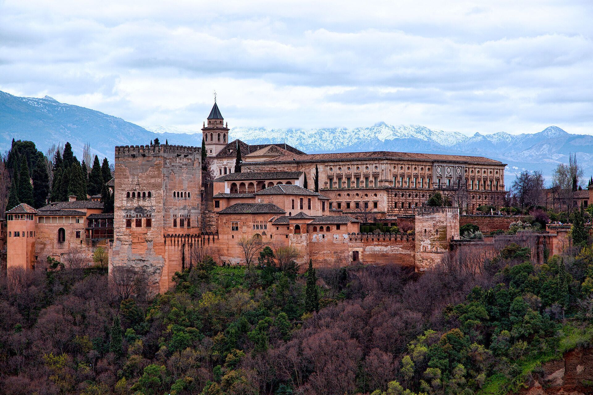 Una fortaleza histórica con una torre destacada y un edificio grande con ventanas arqueadas.