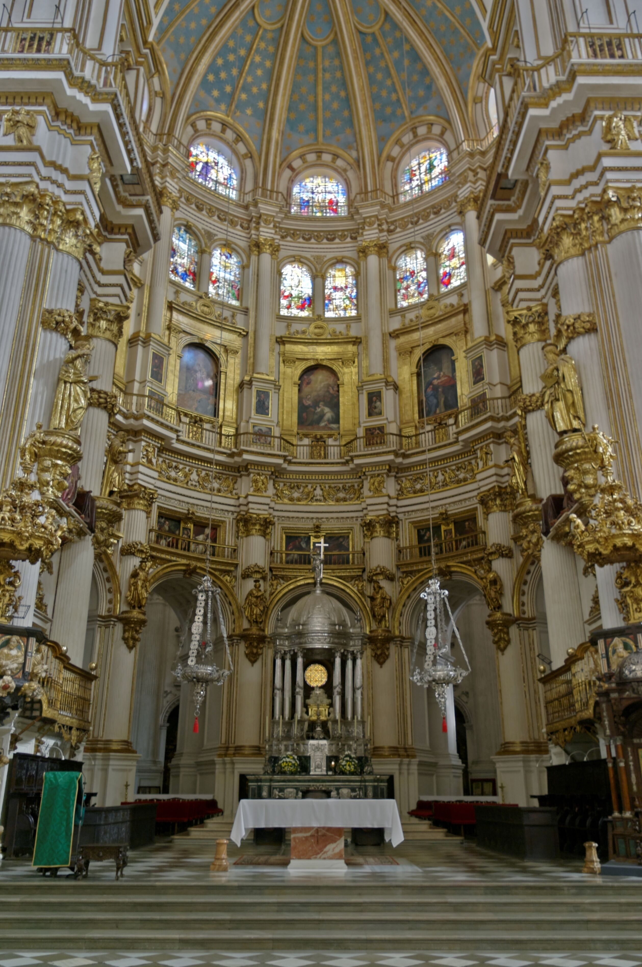 Interior ornamentado de iglesia con techo alto, vidrieras y detalles dorados.