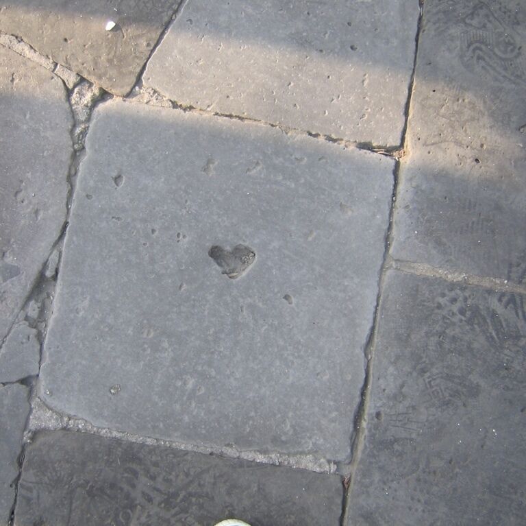 A close-up of a stone pavement with a heart-shaped imprint.