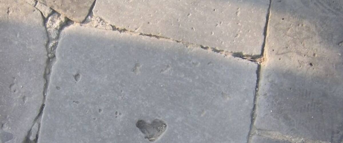 A close-up of a stone pavement with a heart-shaped imprint.