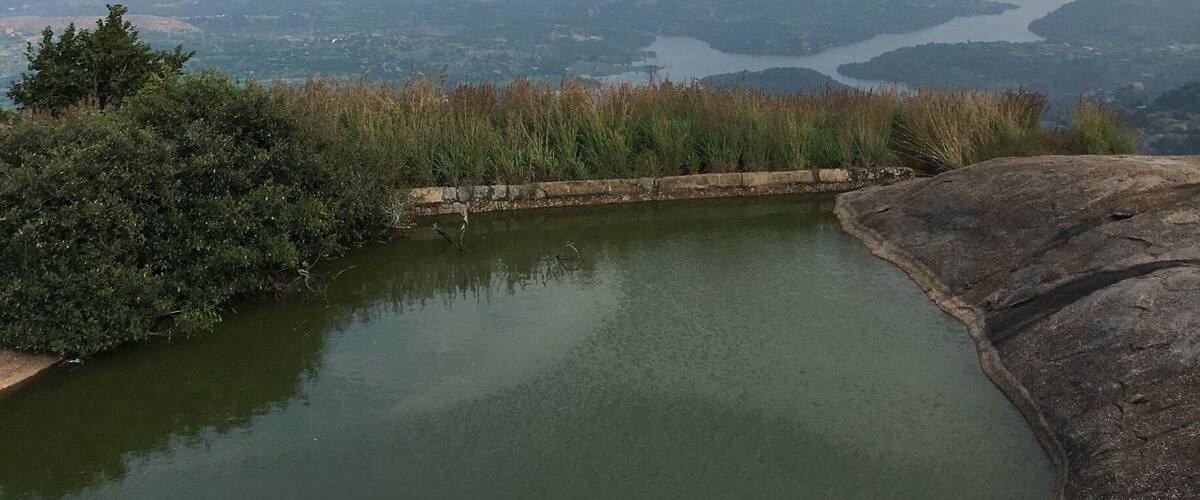 A panoramic view of a lake surrounded by hills and a distant cityscape.