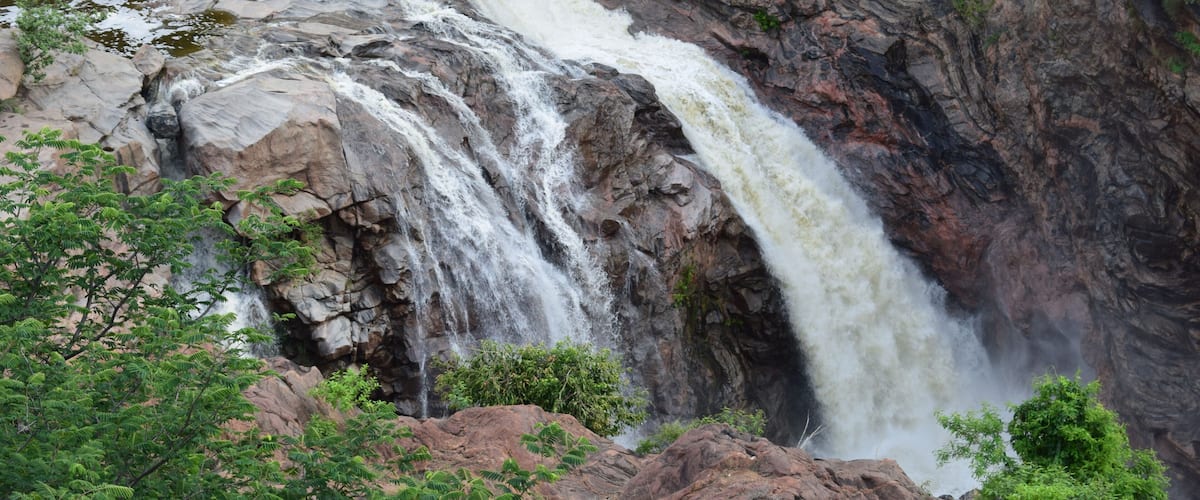 A waterfall cascading down a rocky cliff surrounded by greenery.