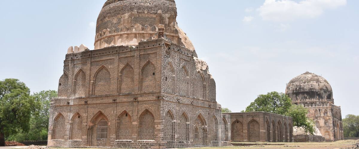An ancient brick structure with domed roofs and arched windows.