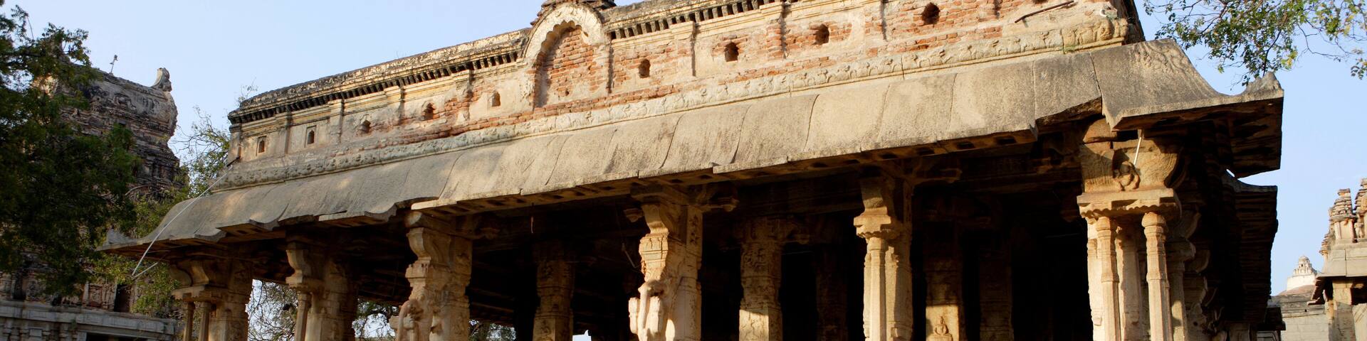 An ancient temple with intricate carvings and a lion statue in front.