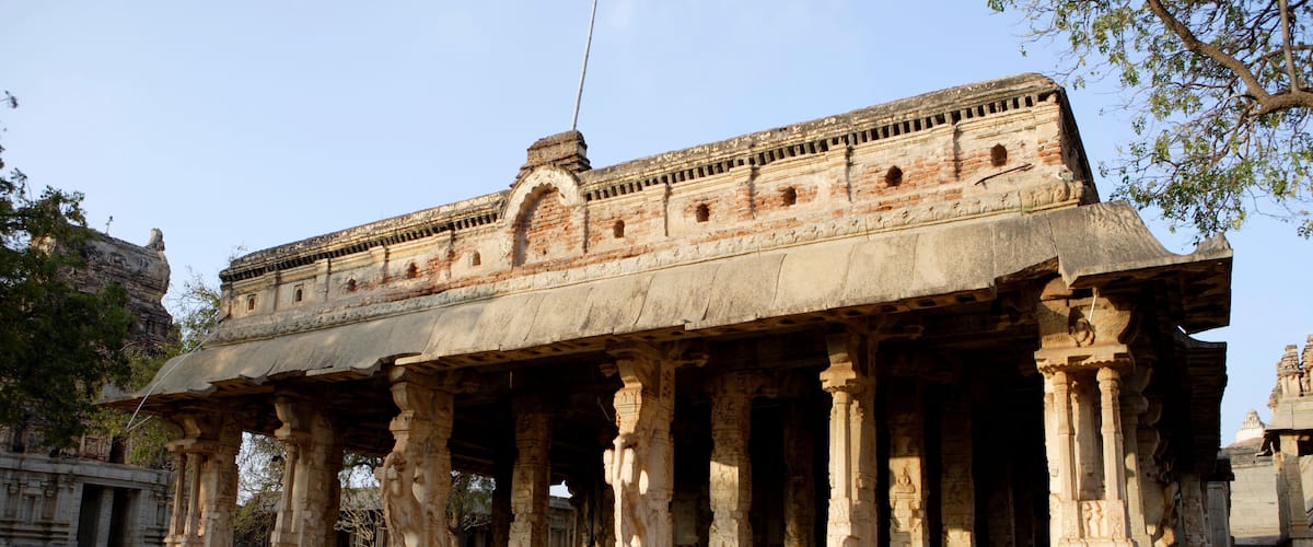 An ancient temple with intricate carvings and a lion statue in front.