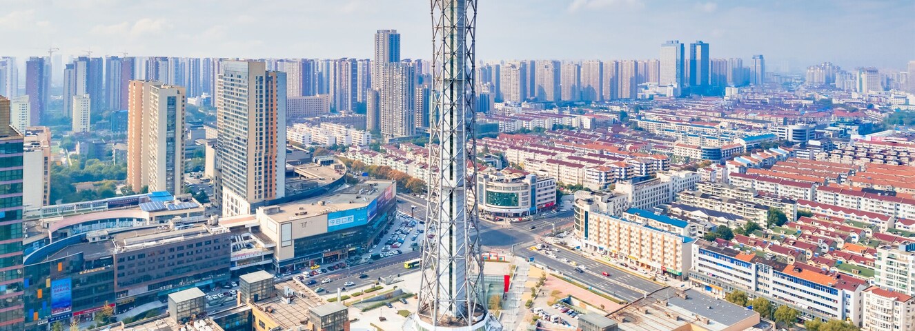 Paisagem urbana com uma torre imponente, rodeada por edifícios altos e uma mistura de construções comerciais e residenciais.