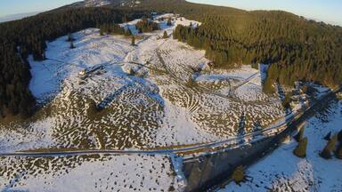 A snow-covered landscape with a winding road and a bridge.
