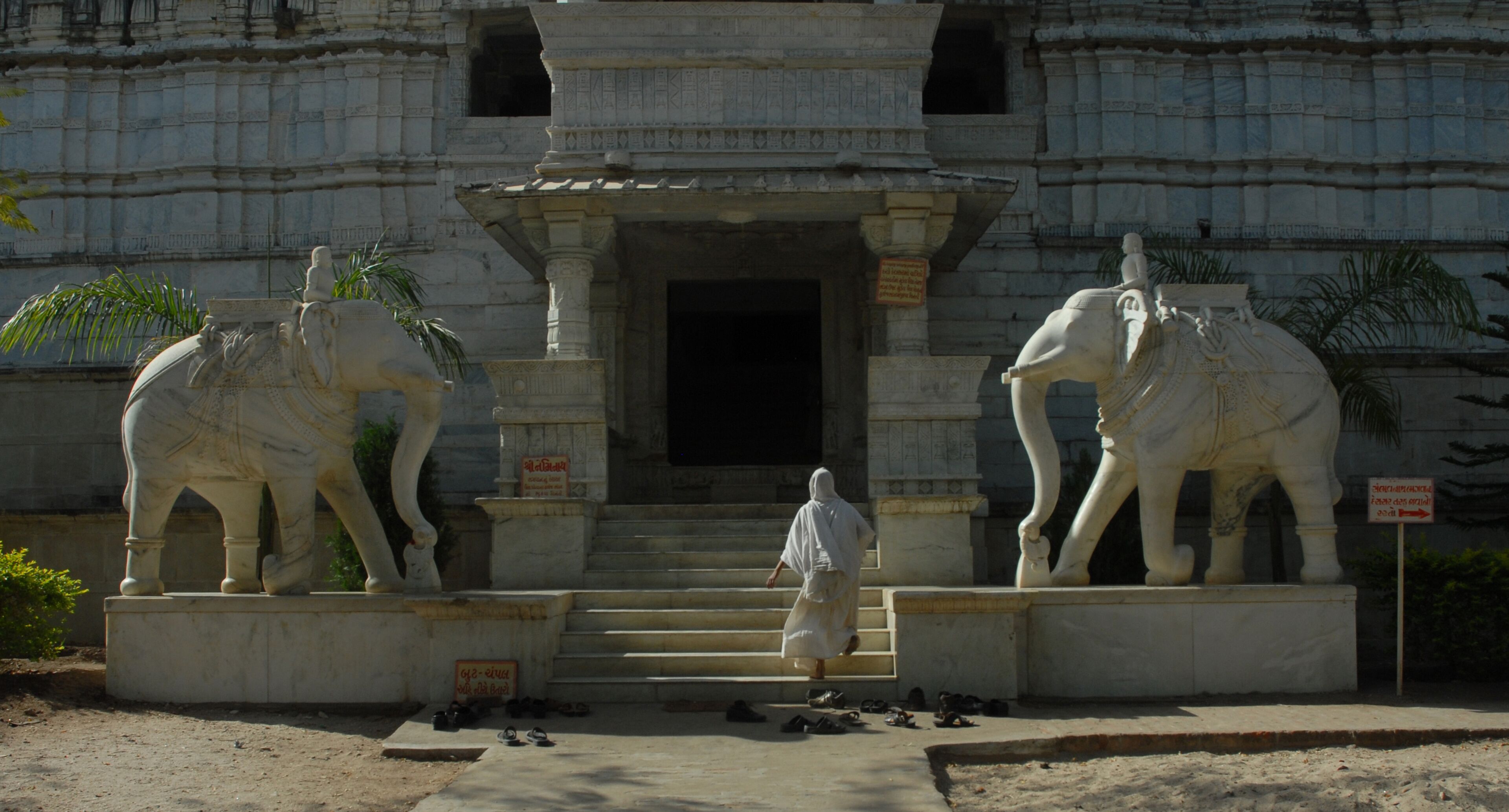 A temple entrance with two large elephant statues and a person walking in front.