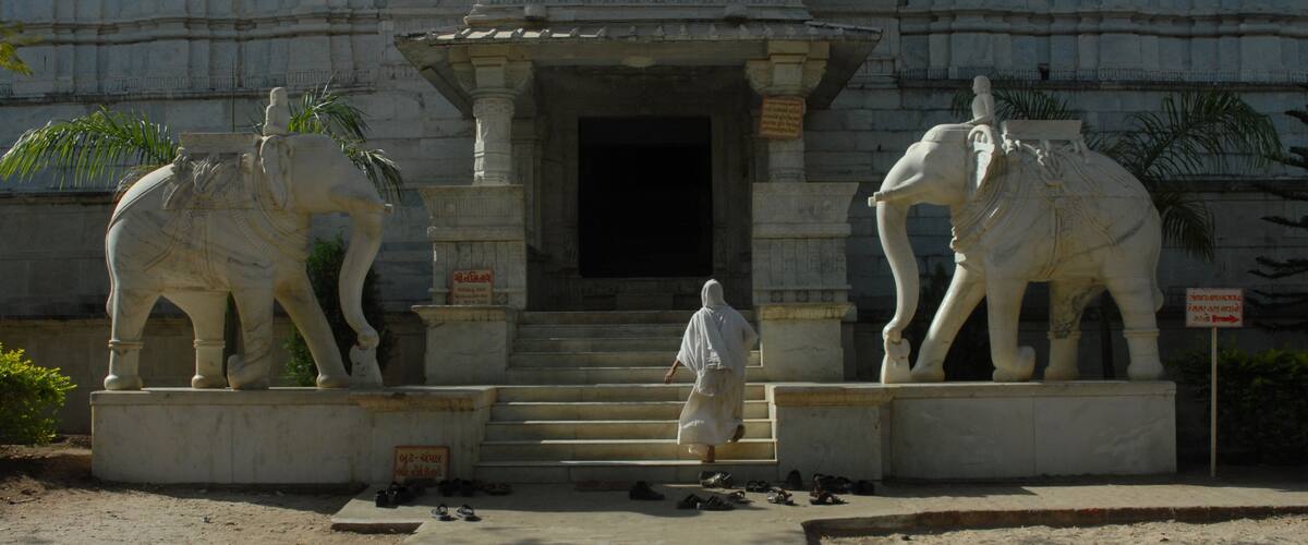 A temple entrance with two large elephant statues and a person walking in front.