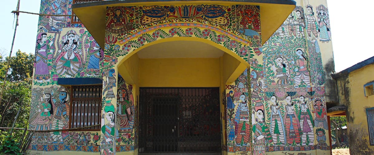 A building with colorful murals and a yellow archway.