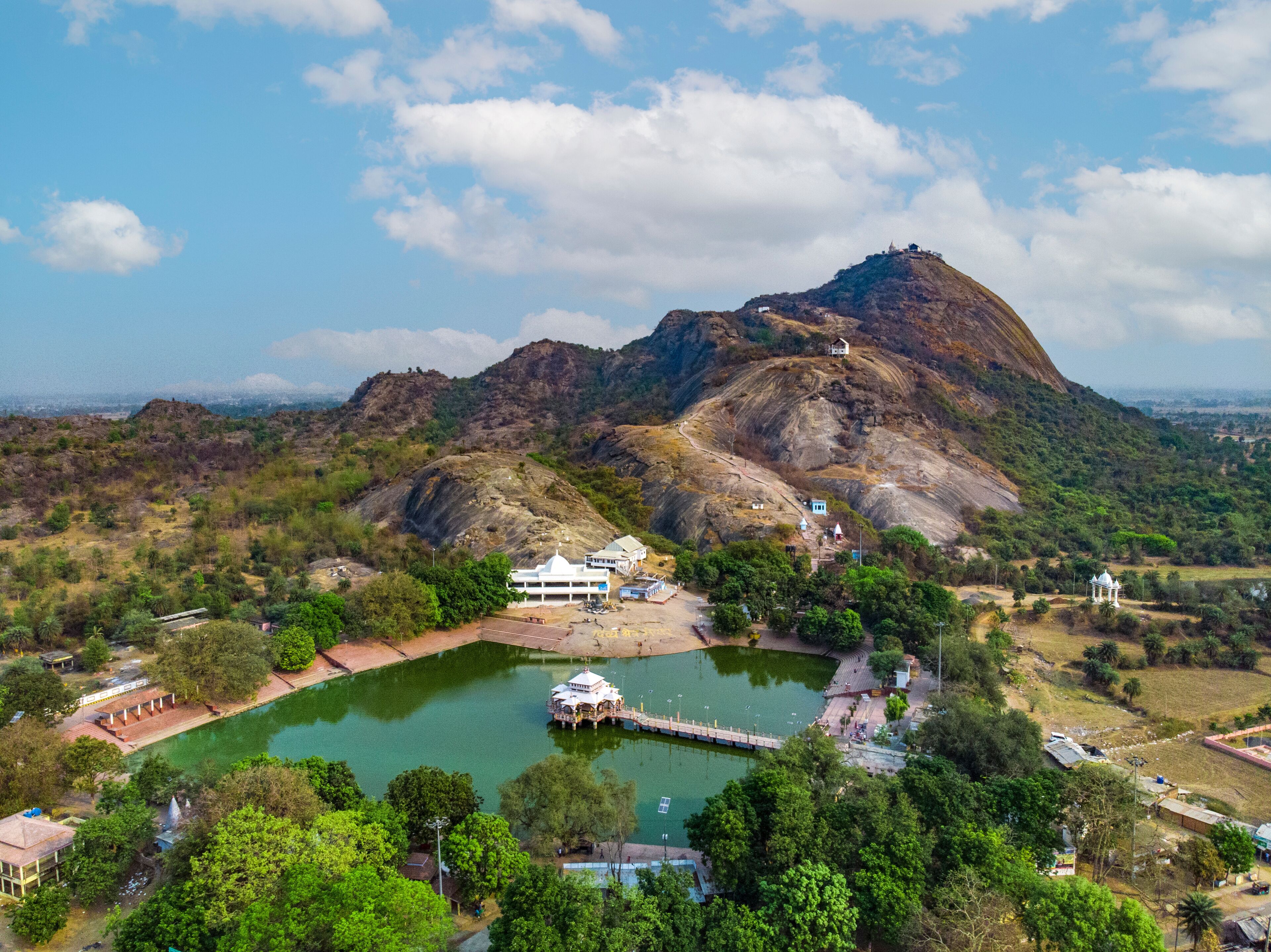 A mountainous landscape with a lake, a temple, and a white building.