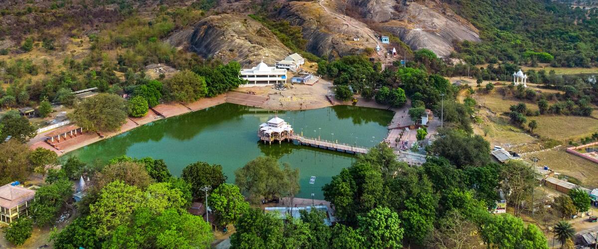 A mountainous landscape with a lake, a temple, and a white building.