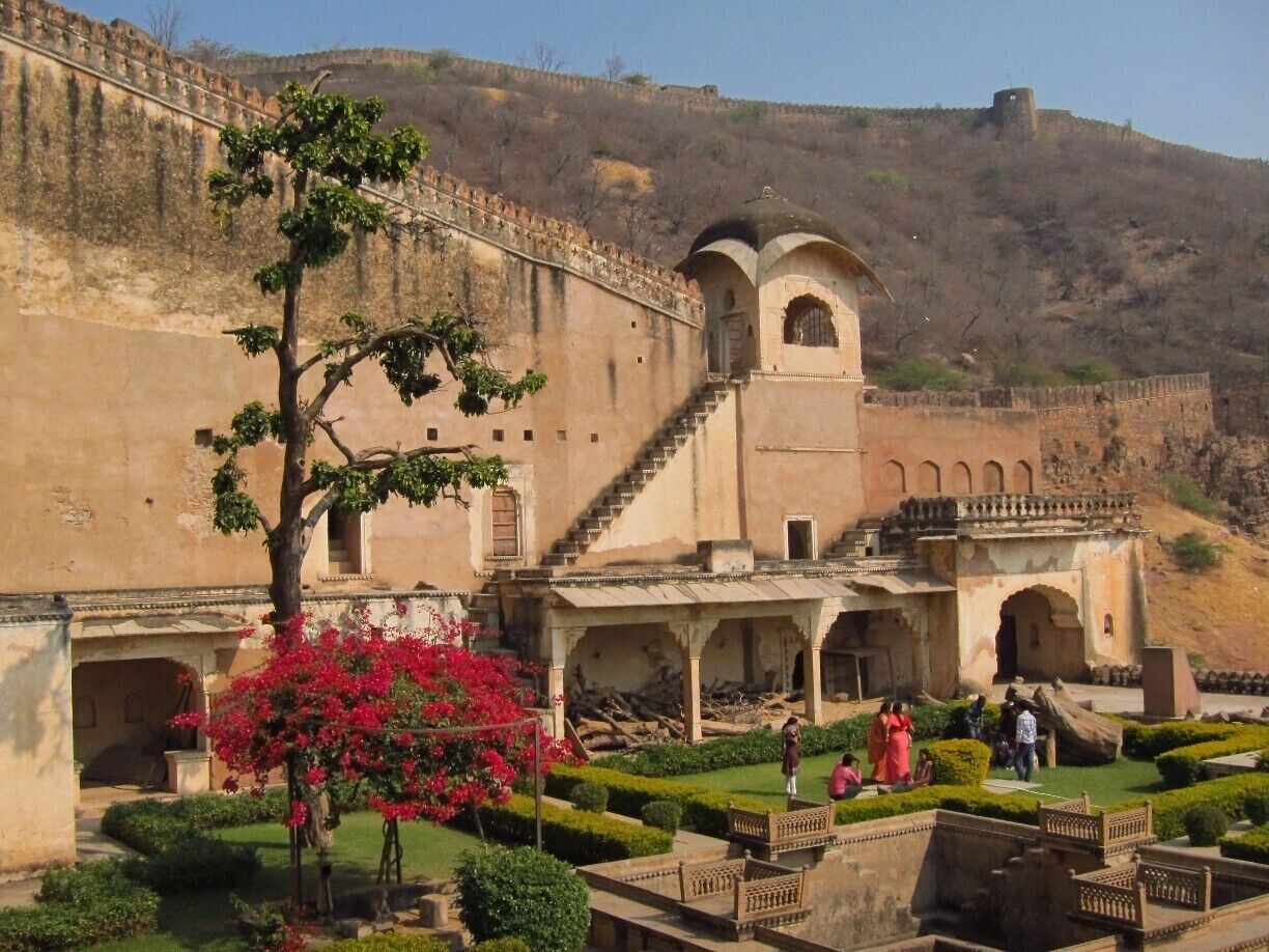 A historic fort with arched gateways and a lush garden with pink bougainvillea.
