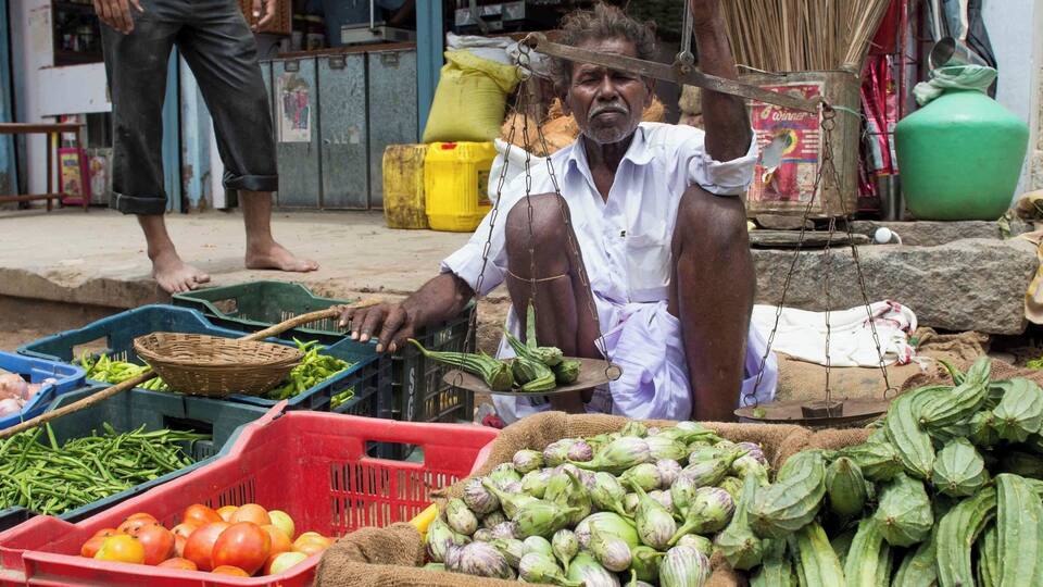 A street vendor selling vegetables at a market.