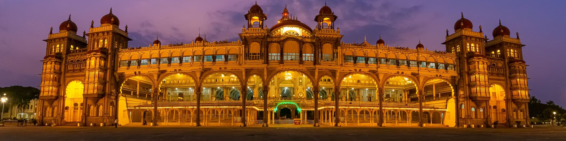 A grand, illuminated building with multiple domes and arches at dusk.