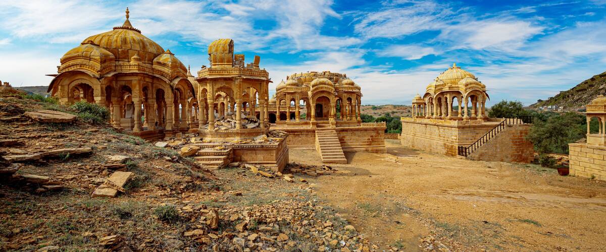 Ancient ruins with domed structures and arches under a clear blue sky.