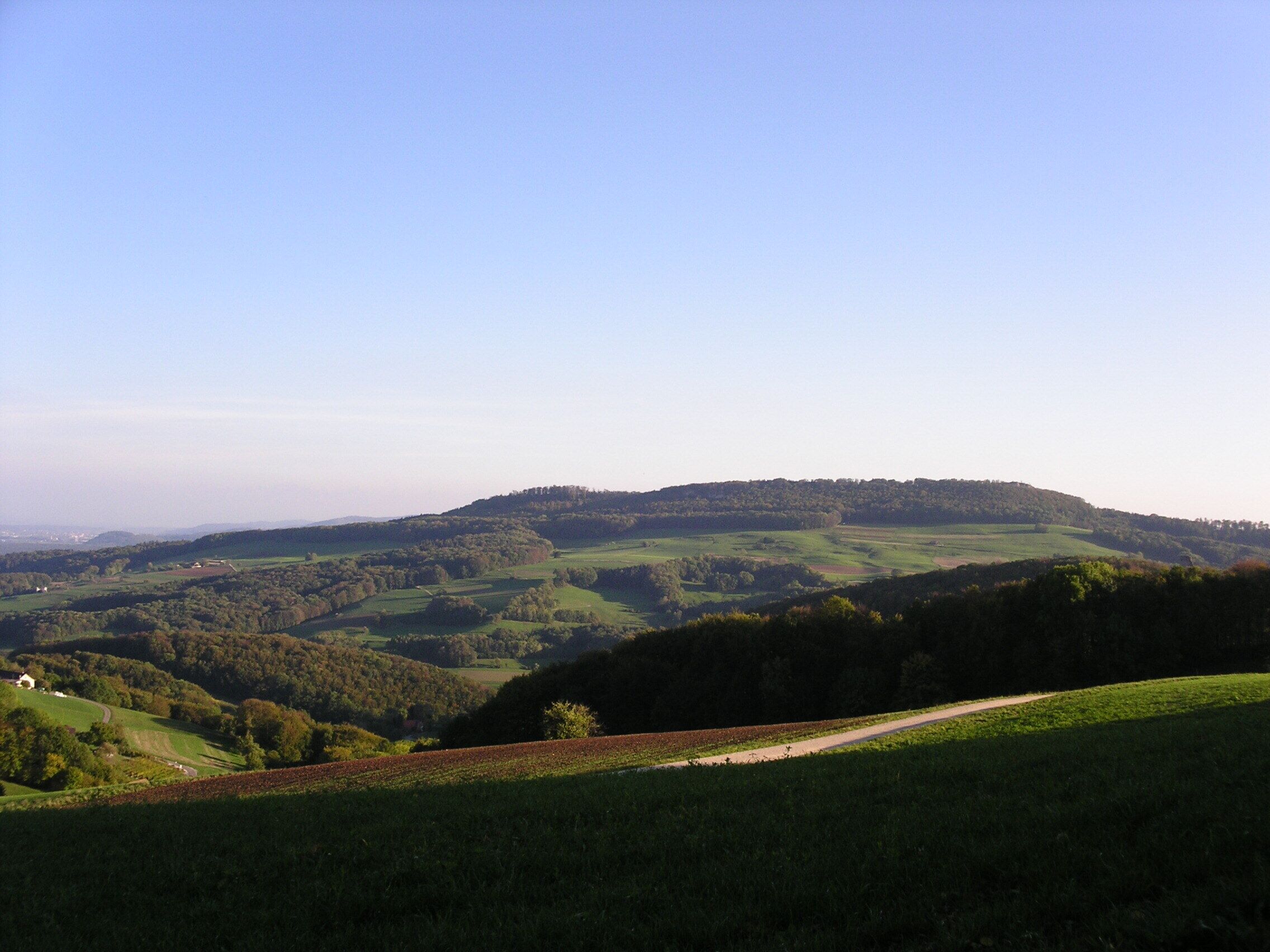 Rolling hills, a clear sky, and a distant building.