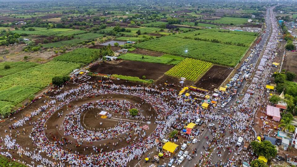 An aerial view of a large gathering in a circular formation with surrounding fields and roads.